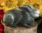 Two rabbit statues on wooden stump in front of brightly colored flowers - selective focus