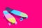 Two rainbow plastic Penny board skateboards on crimson background