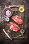 Two raw beef steaks with wine in glass, herbs, oil and spices.