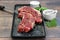 Two raw beef strip steaks on a black prep dish. Selective focus