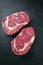 Two raw dry aged Angus Entrecote Steak offered on a black board