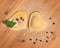 Two raw handmade ravioli ,open and closed,in the shape of heart,covered with flour and placed on wooden table