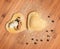 Two raw homemade ravioli,open and closed,in the shape of heart,covered with flour and placed on wooden table.