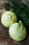 Two raw kohlrabies with some herbs dill, parsley and chives on a rustic wooden table.