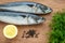 Two raw mackerels, bunch of fresh dill, black peppercorns and lemon on a brown wooden cutting board. Seafood, healthy eating and