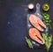 Two raw steak to salmon, seafood, healthy food with herbs, parsley, olive oil and salt dark vintage cutting board on wooden rus