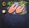 Two raw steak to salmon, seafood, healthy food with herbs, parsley, olive oil and salt dark vintage cutting board on wooden rus