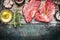 Two raw steaks with oil and spices on dark rustic background, top view