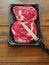 Two raw uncooked premium fresh rib eye steaks on a plastic tray, Top quality product from supermarket. On a wooden table