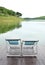 Two Recline chairs on dock facing a green lake.