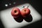 Two red apples that can symbolize two full breasts or two muscular testicles in which is planted a syringe