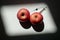 Two red apples that can symbolize two full breasts or two muscular testicles in which is planted a syringe