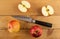 Two red apples, halves of apple, knife on wooden table. Top view