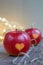 Two red apples with a heart seal on the table. Orange heart on organically grown fruits. Growing fruits with prints.