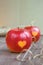 Two red apples with a heart seal on the table. Orange heart on organically grown fruits. Growing fruits with prints