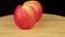 Two red apples rotate 360 degrees on a wooden stand