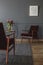 Two red armchairs standing in a dark gray living room interior w