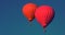 Two Red balloons in the sky. Aerostat. People in the basket. Fun. Summer entertainment. Romantic adventures. Modern toned photo