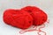 Two red balls (clews) of yarn and knitting hook