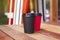 Two red and black paper cups to takeaway on wooden floor outside the cafe. Surfing boards stand behind at the background.