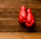 Two red boxing gloves hung on a wooden brown background