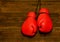 Two red boxing gloves hung on a wooden brown background, empty space