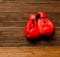 Two red boxing gloves hung on a wooden brown background, empty space