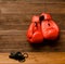 Two red boxing gloves hung on a wooden brown background, skipping rope