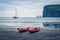 Two red canoes on the Atlantic coast. Amazing afternoon scene of Streymoy island with Eidiskollur cliffs on background, Faroe Isla