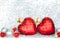 Two red Christmas tree glass balls in the shape of heart with golden stars and silver and red balls on shiny sparkling tinsel