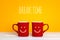 Two red coffee mugs with a smiling faces on a yellow background