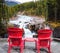 Two red deckchairs stand on the shore