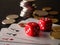 Two red dice, game cards and stack of coins