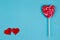 Two red fabric hearts and sweet bright lollipop heart on blue ba