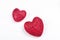 Two red glittering hearts on white wooden background