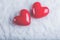 Two red glossy hearts on a frosty white snow background. Love and St. Valentine concept.