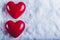 Two red glossy hearts on a frosty white snow background. Love and St. Valentine concept.