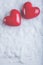 Two red glossy hearts on a frosty white snow background. Love and St. Valentine concept.