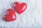 Two red glossy hearts on a frosty white snow background. Love and St. Valentine concept.