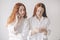 Two red-haired sisters stand isolated on a white background in spacious oversized shirts. Two young women are addicted