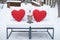two red heart cushions on white snowcovered outdoor loveseat