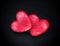 Two red hearts on a dark background, soft focus. Romantic card.