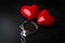 Two red hearts and steel handcuffs on dark background.St Valenti