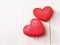 Two red hearts on a wooden white background, soft focus. Romantic card.
