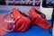 Two red karate fighting helmet with clear plastic masks and two body protective vests on the floor