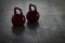 Two red kettlebells on a stone floor in a gym - background light