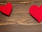 Two red large hearts on a wooden brown background on the sides. Shadow from the heart. Place for text. Happy