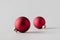 Two red matte Christmas balls on a seamless grey background