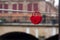 two red padlocks in shaped heart on metallic cable in border water