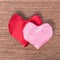 Two red and pink hand-sewn heart on wooden background, concept V